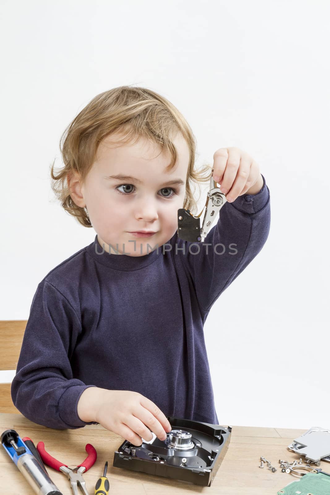 young child repairing open hard disk drive with different tools