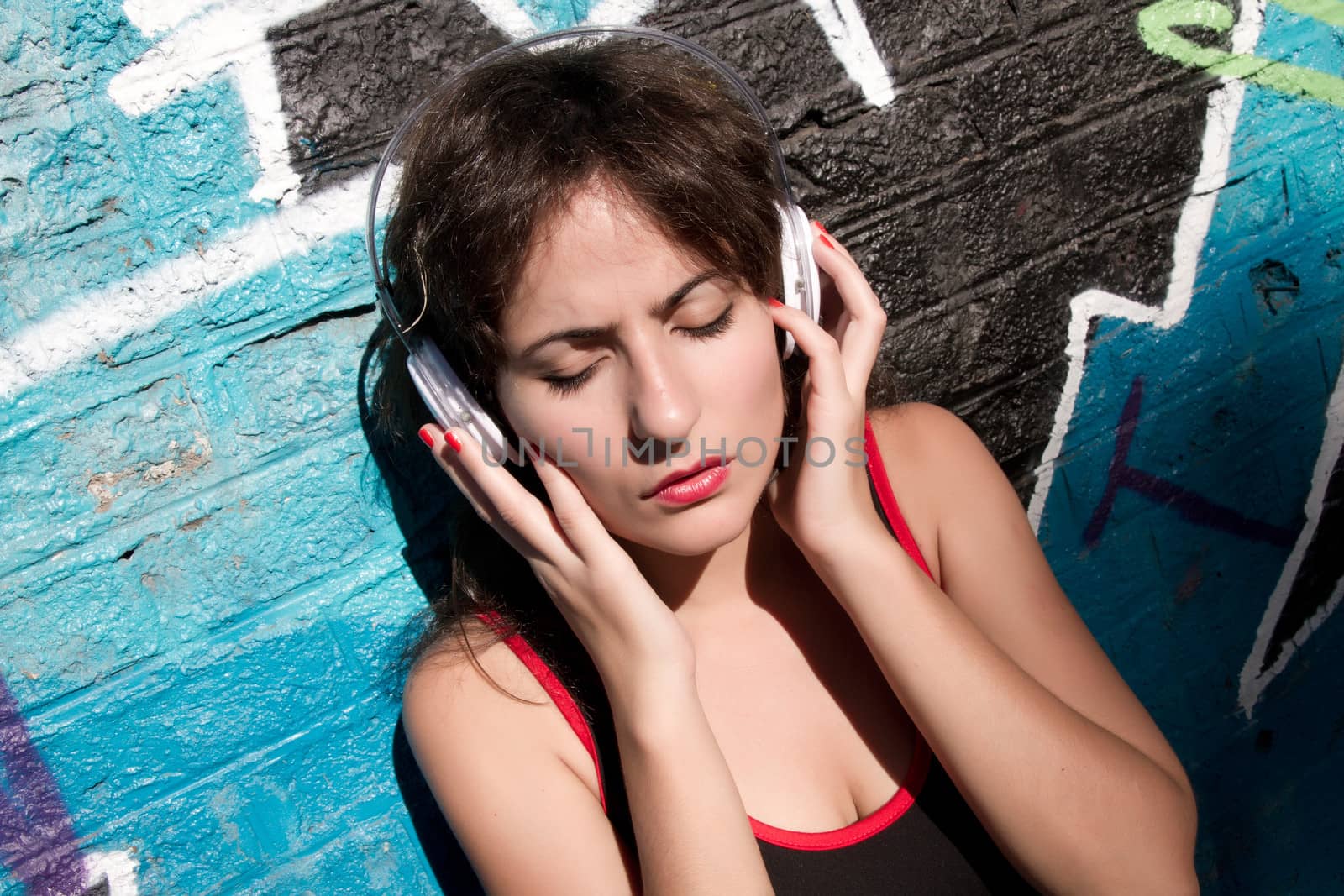 A vintage dressed girl listing to music in a urban environment.