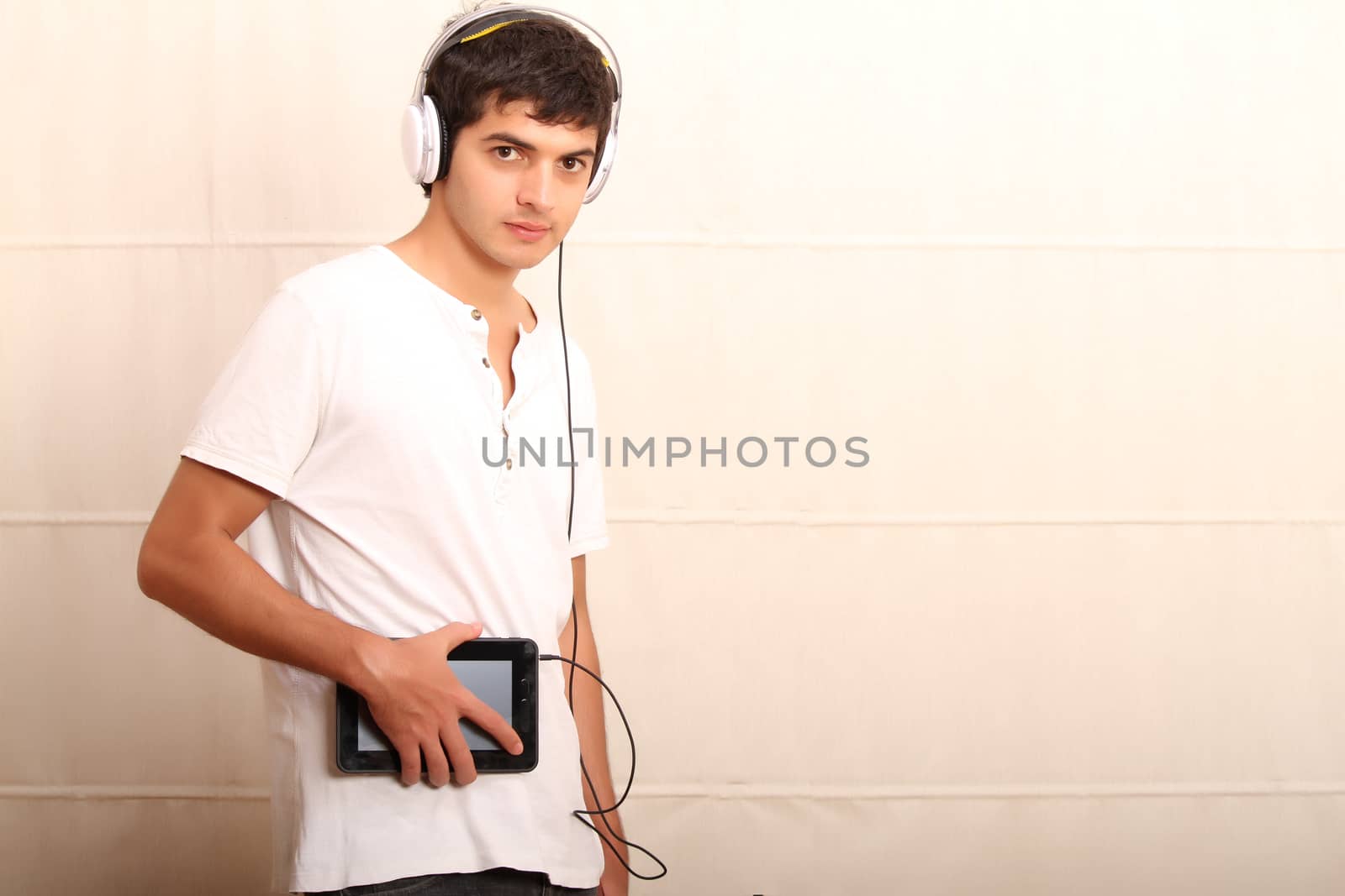 A young, latin man with a Tablet PC and headphones
