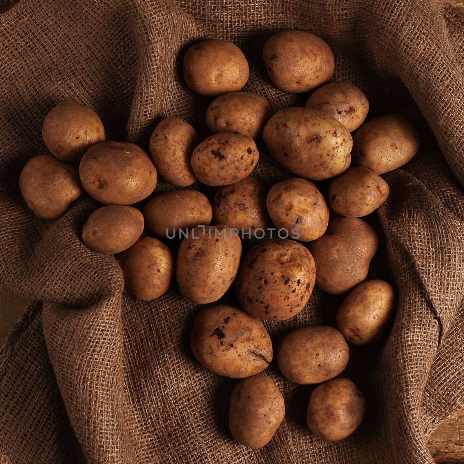 Rustic fresh unpeeled potatoes on a wooden desks