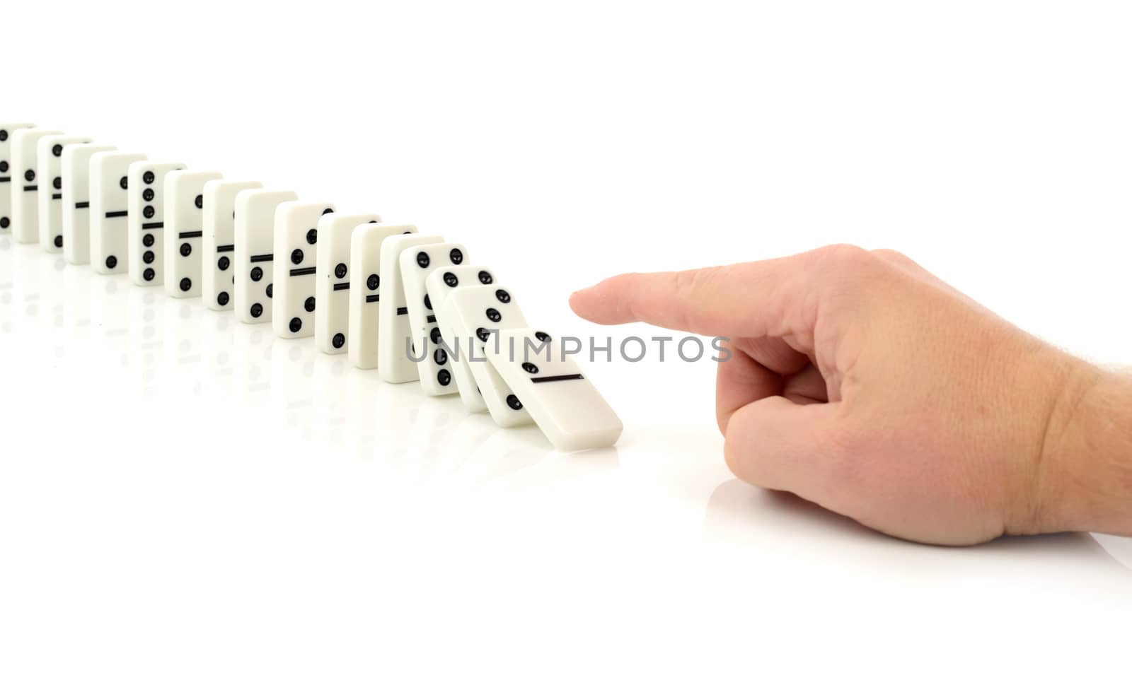 Concept of starting a process or chain reaction of events, finger pushing a domino isolated on a white background