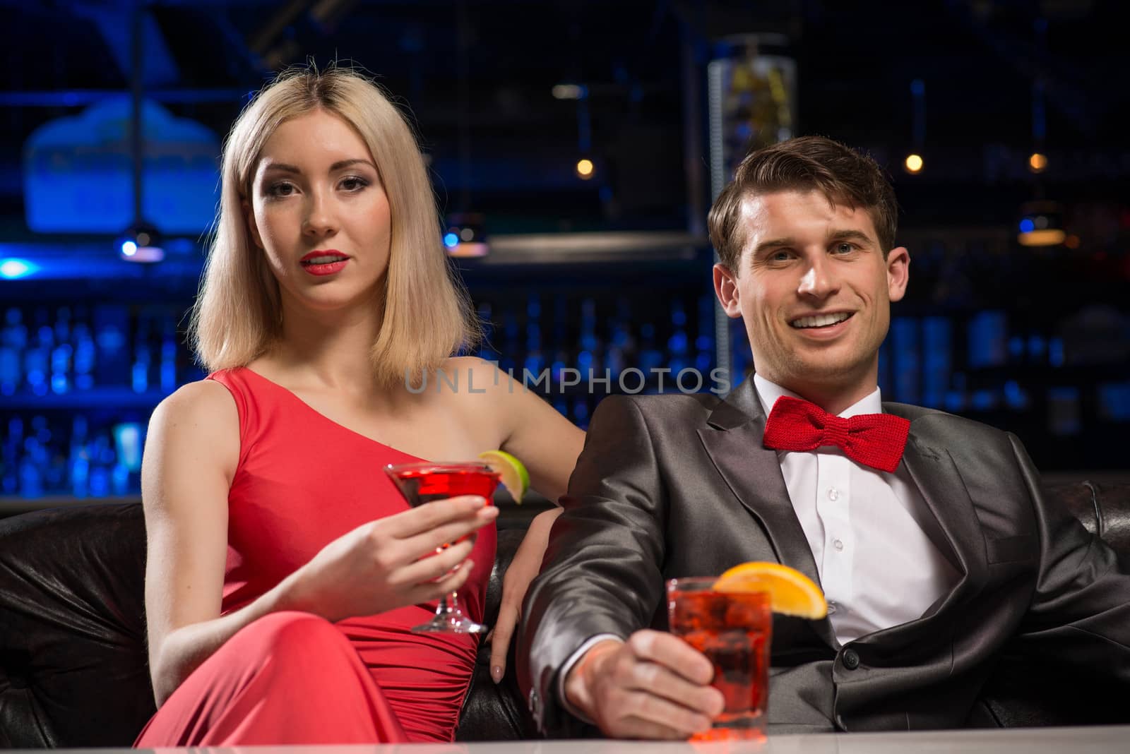 couple in a nightclub on the couch with a drink, have fun