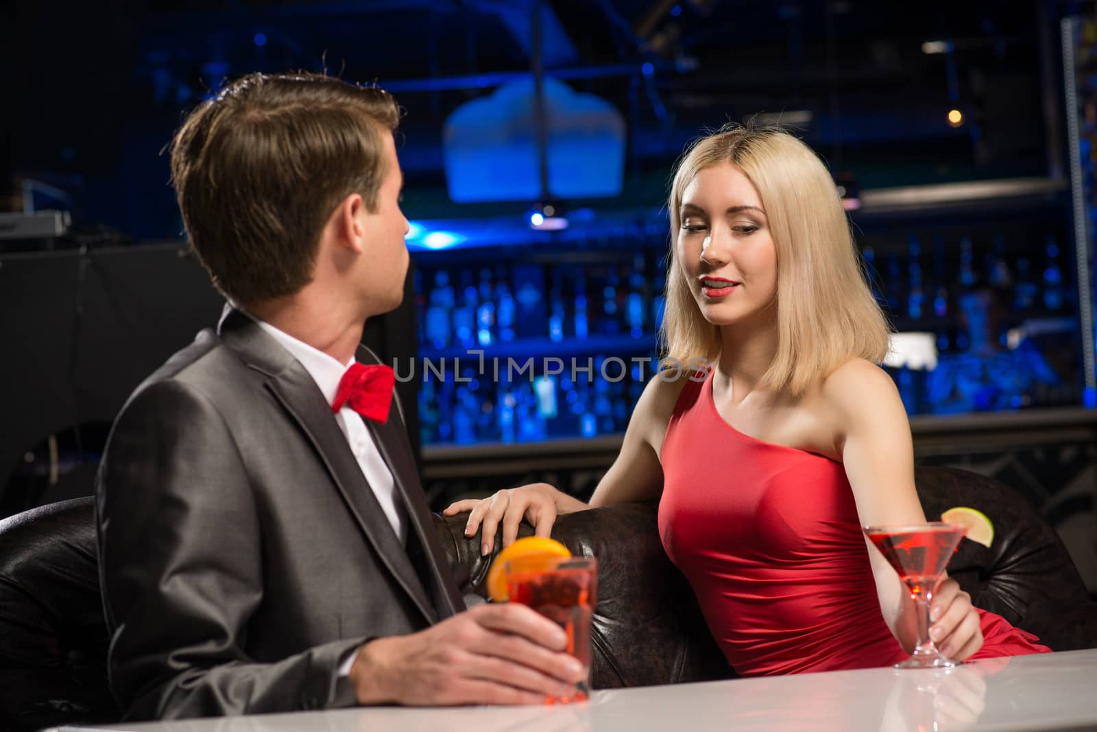 portrait of a woman in a nightclub, sitting on the couch and talking with man