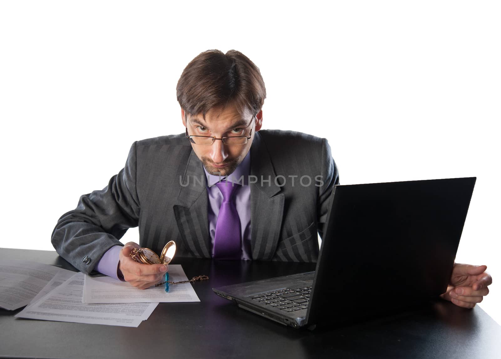 businessman in glasses behind a desk in an office with a clock in his hands