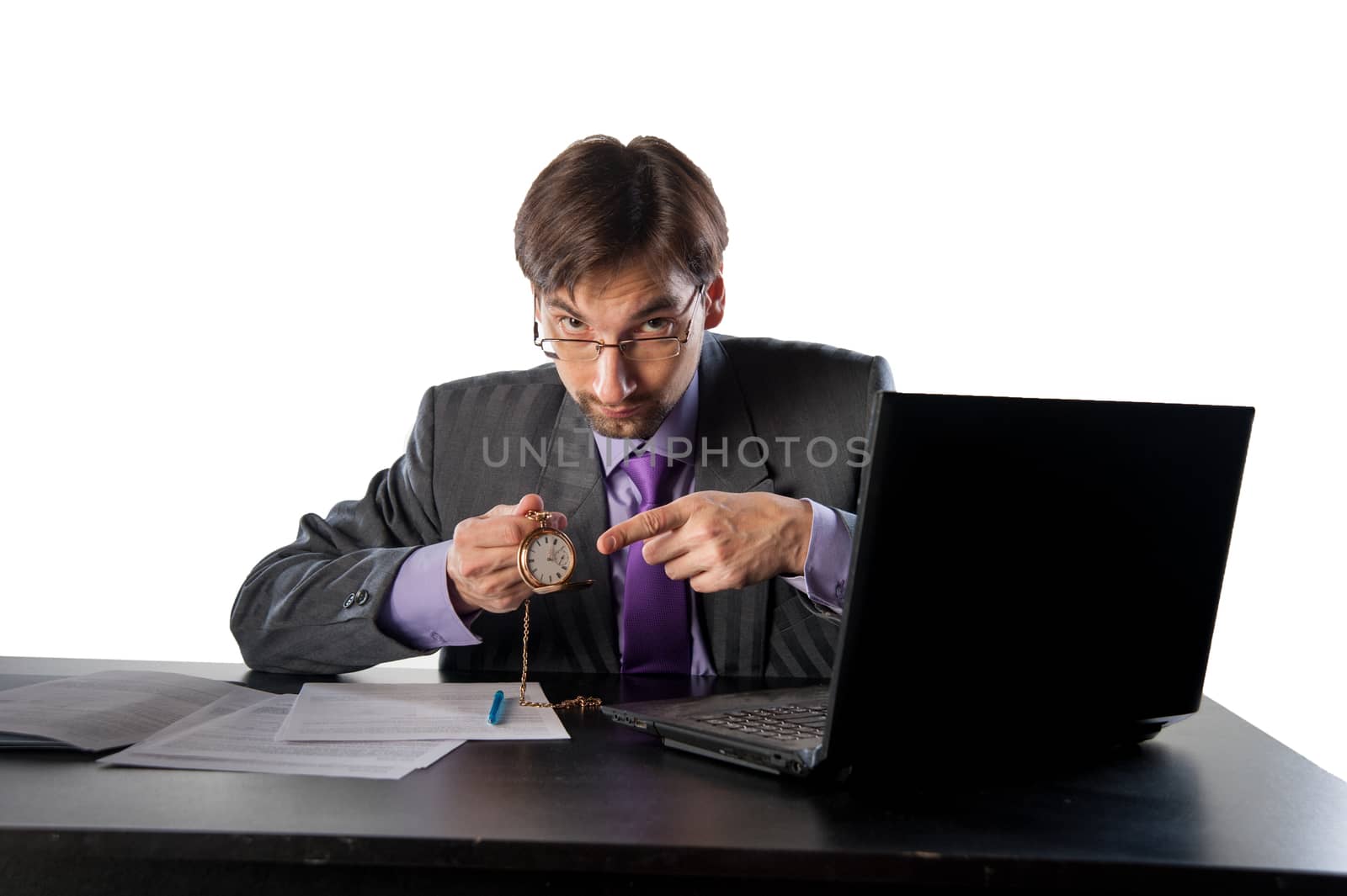 businessman in glasses behind a desk in an office with a clock in his hands