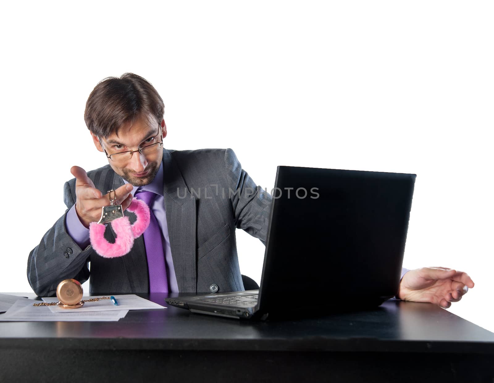 young businessman at his desk offers pink handcuffs
