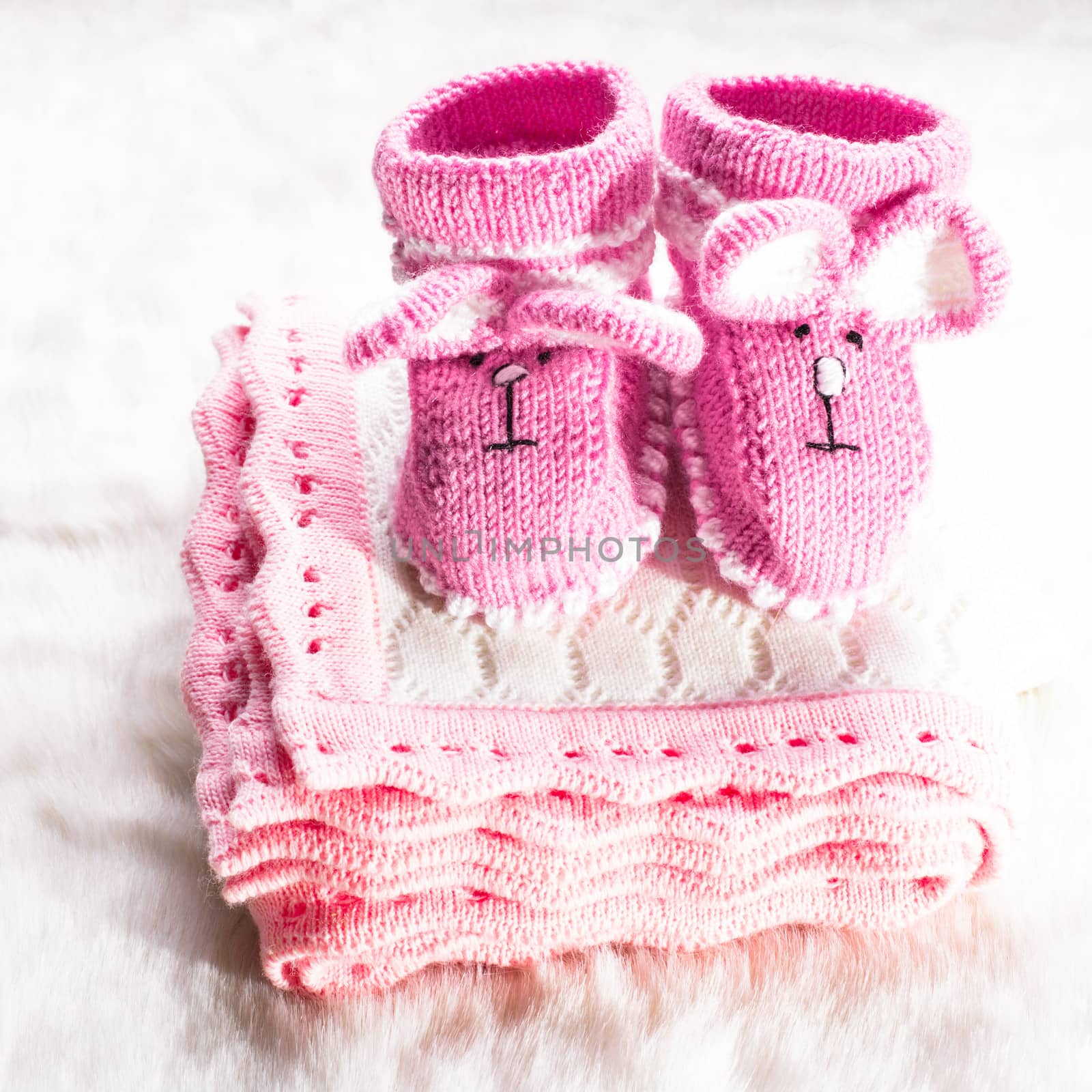 Knitted pink baby booties and blanket for little girl