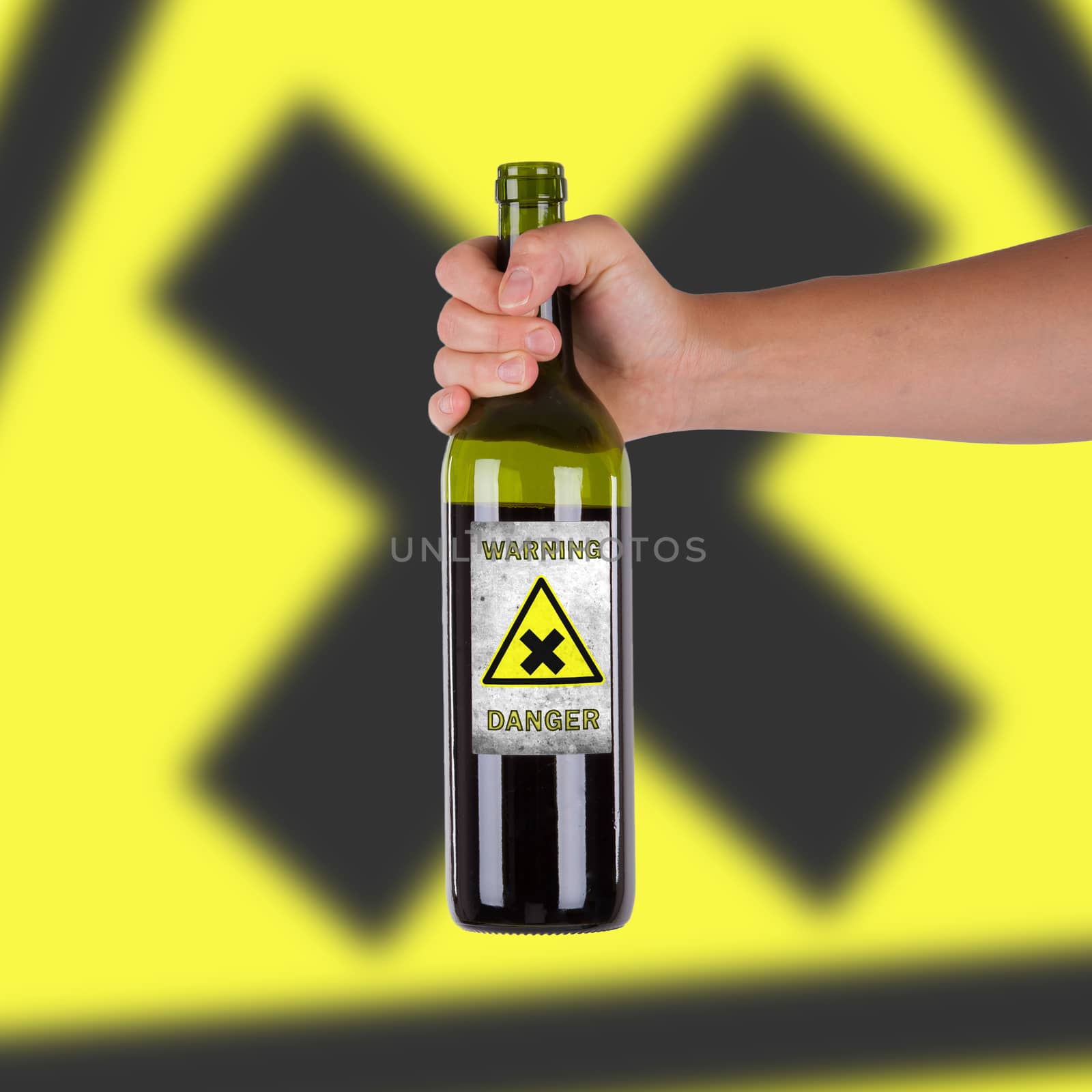 Hand holding a bottle with a warning, danger