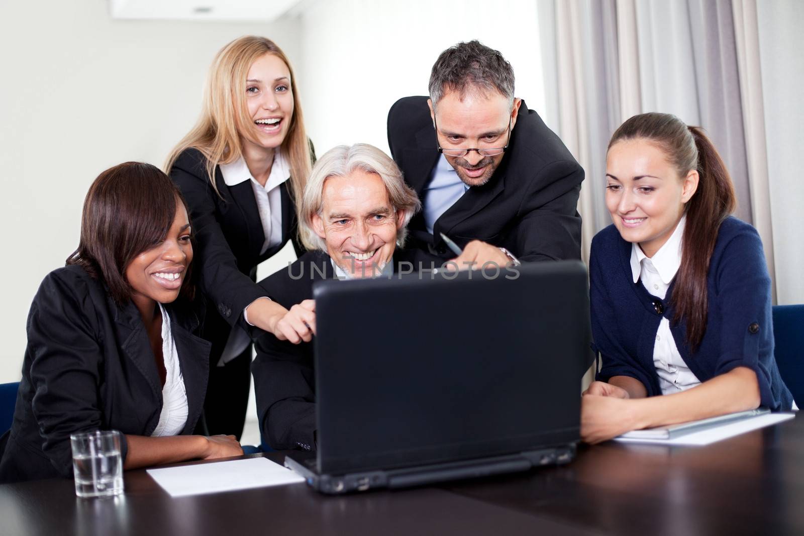 Handsome business manager showing a presentation on his laptop to the team at a meeting