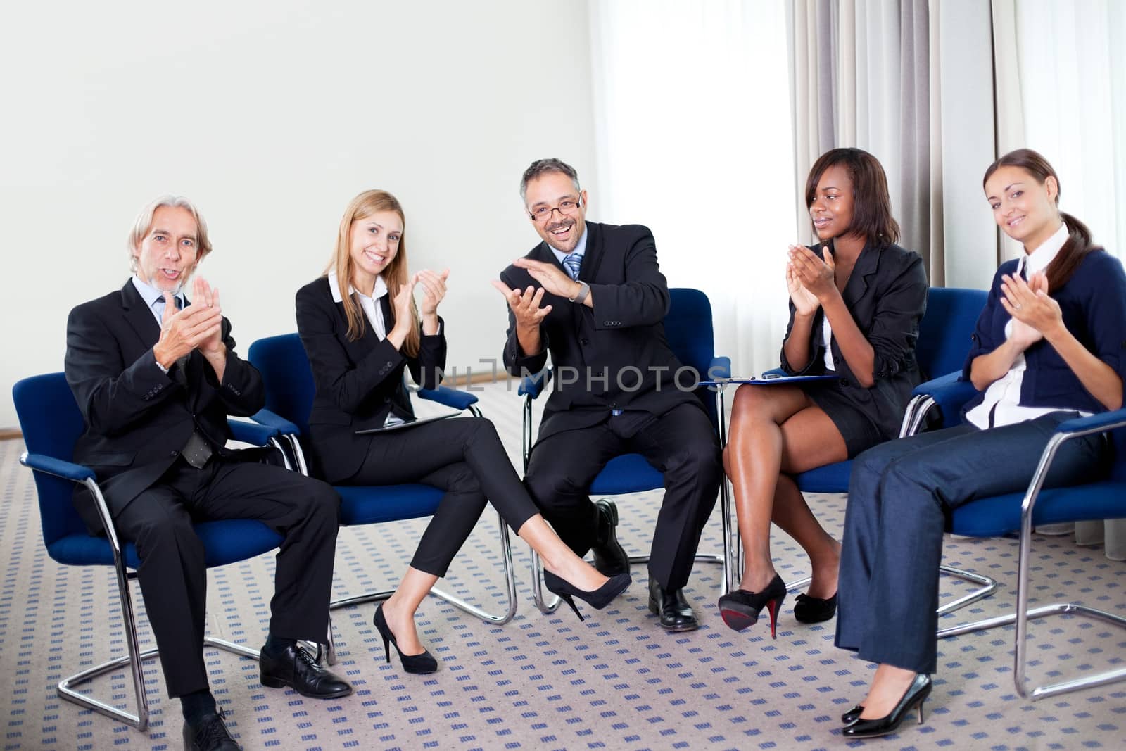 Portrait of a team of happy successful businesspeople sitting together smiling and celebrating at the office