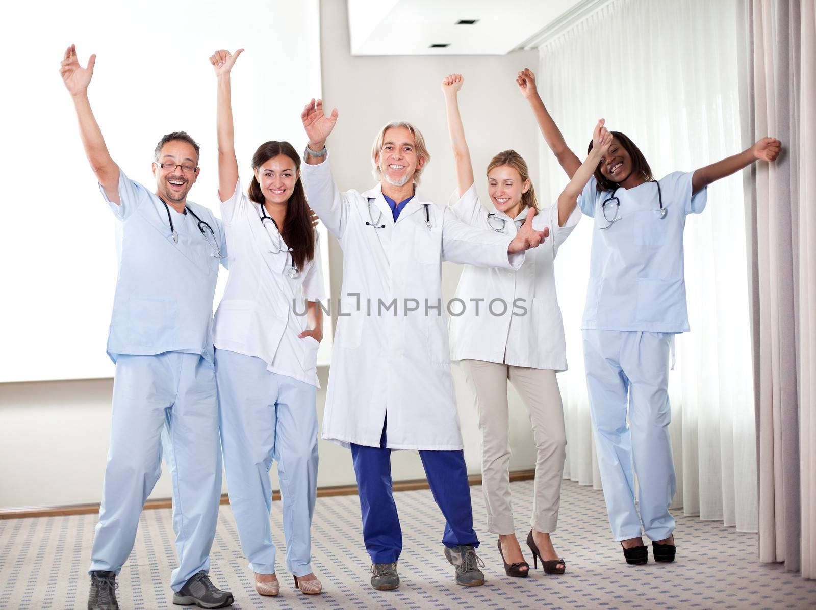 Group of happy doctors smiling and waving after a successful surgey at a hospital