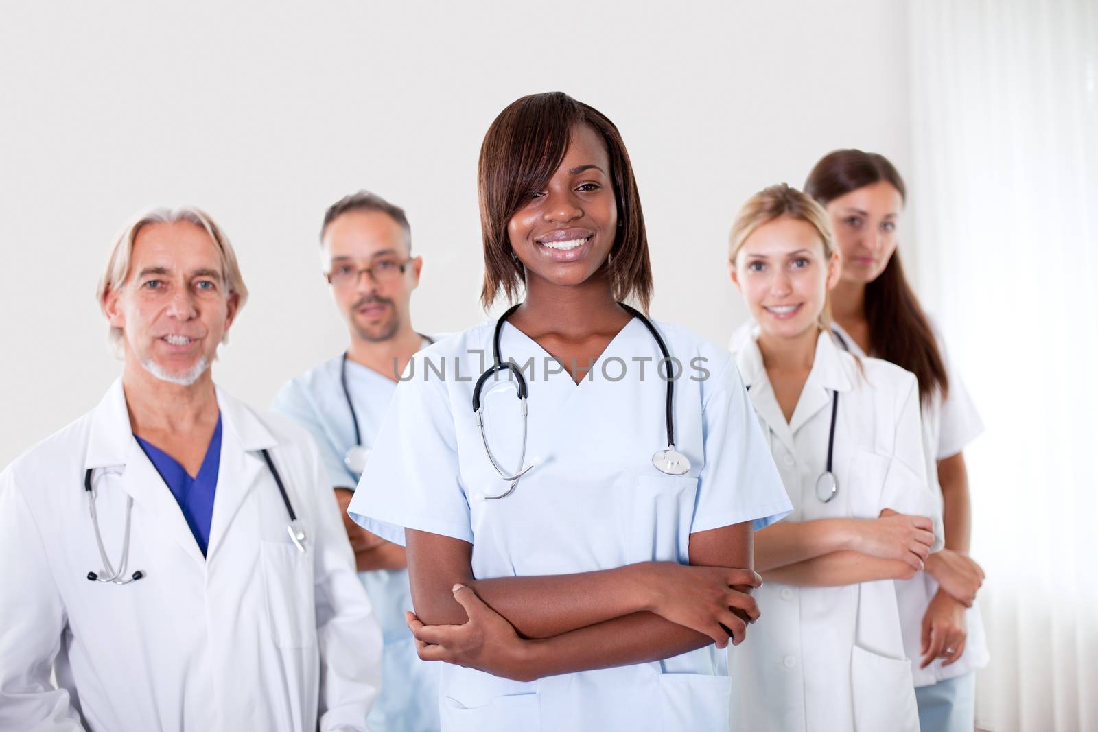 Close-up portrait of pretty young female doctor with colleagues in the background