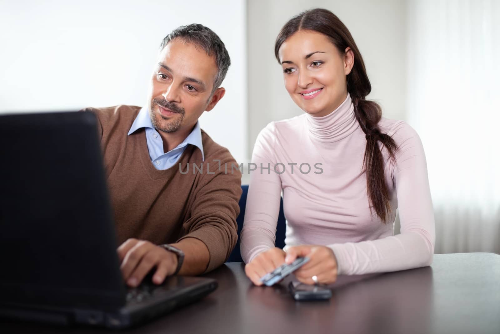 Beautiful young woman sitting with a man using laptop at office.