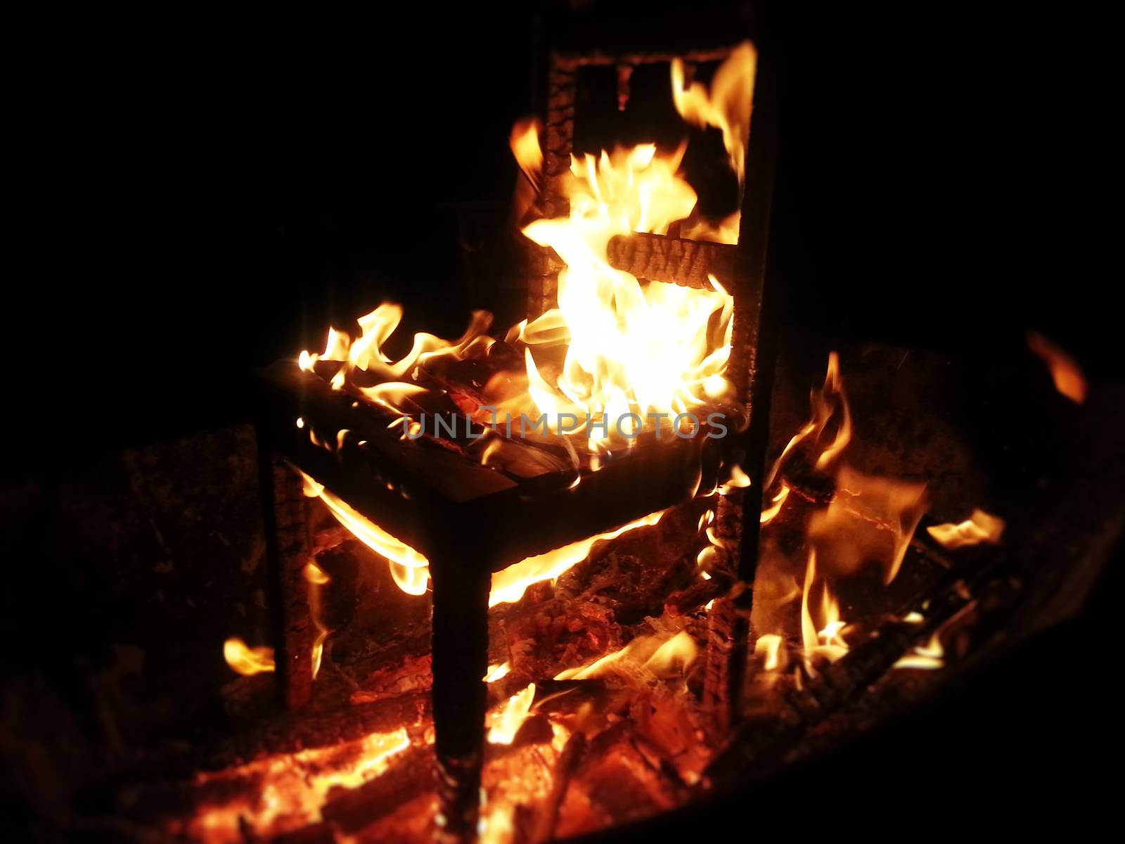 Wood chair burning inside bonfire.