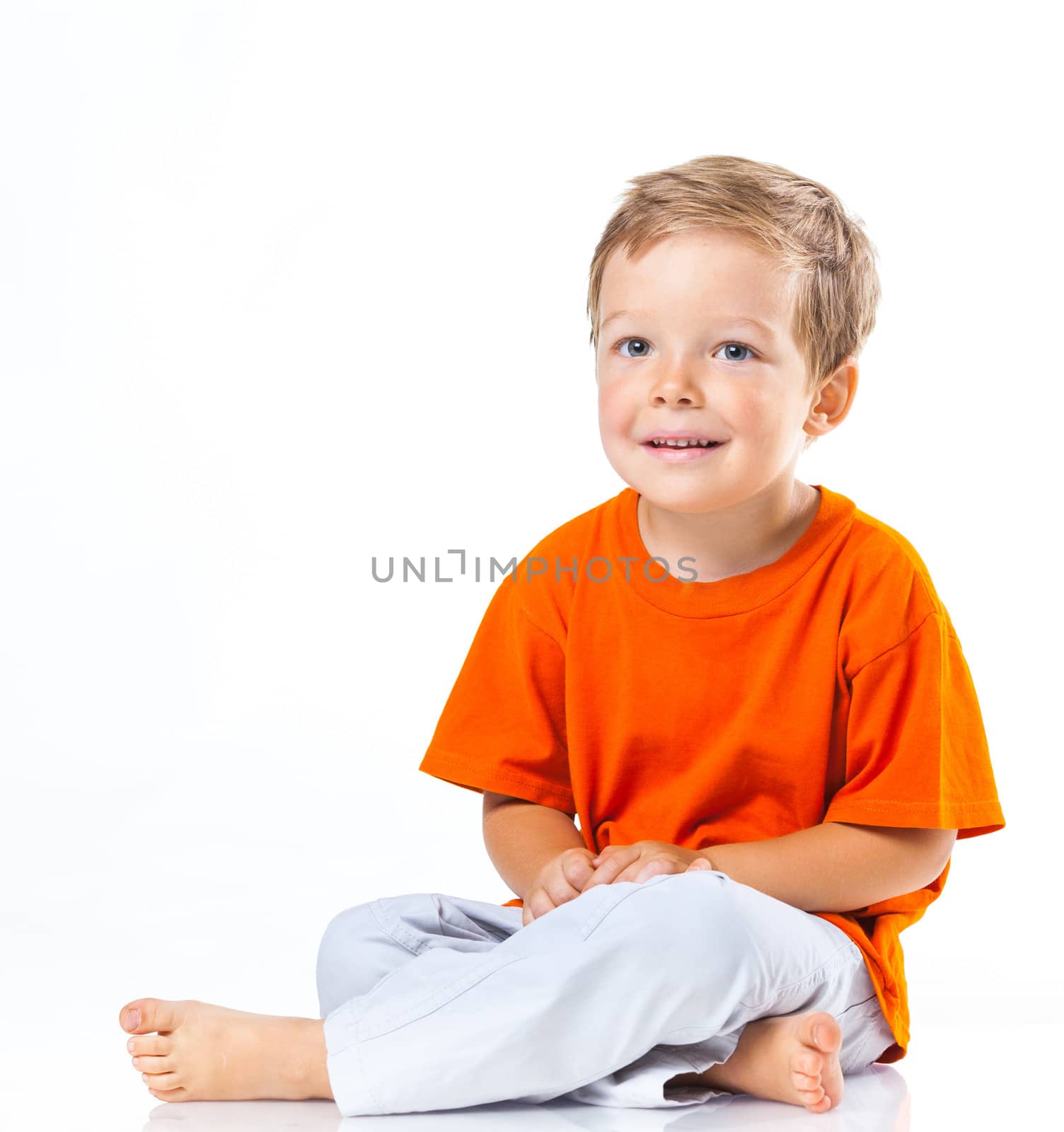 Adorable happy boy sitting on the floor in studio. Isolated of white background.