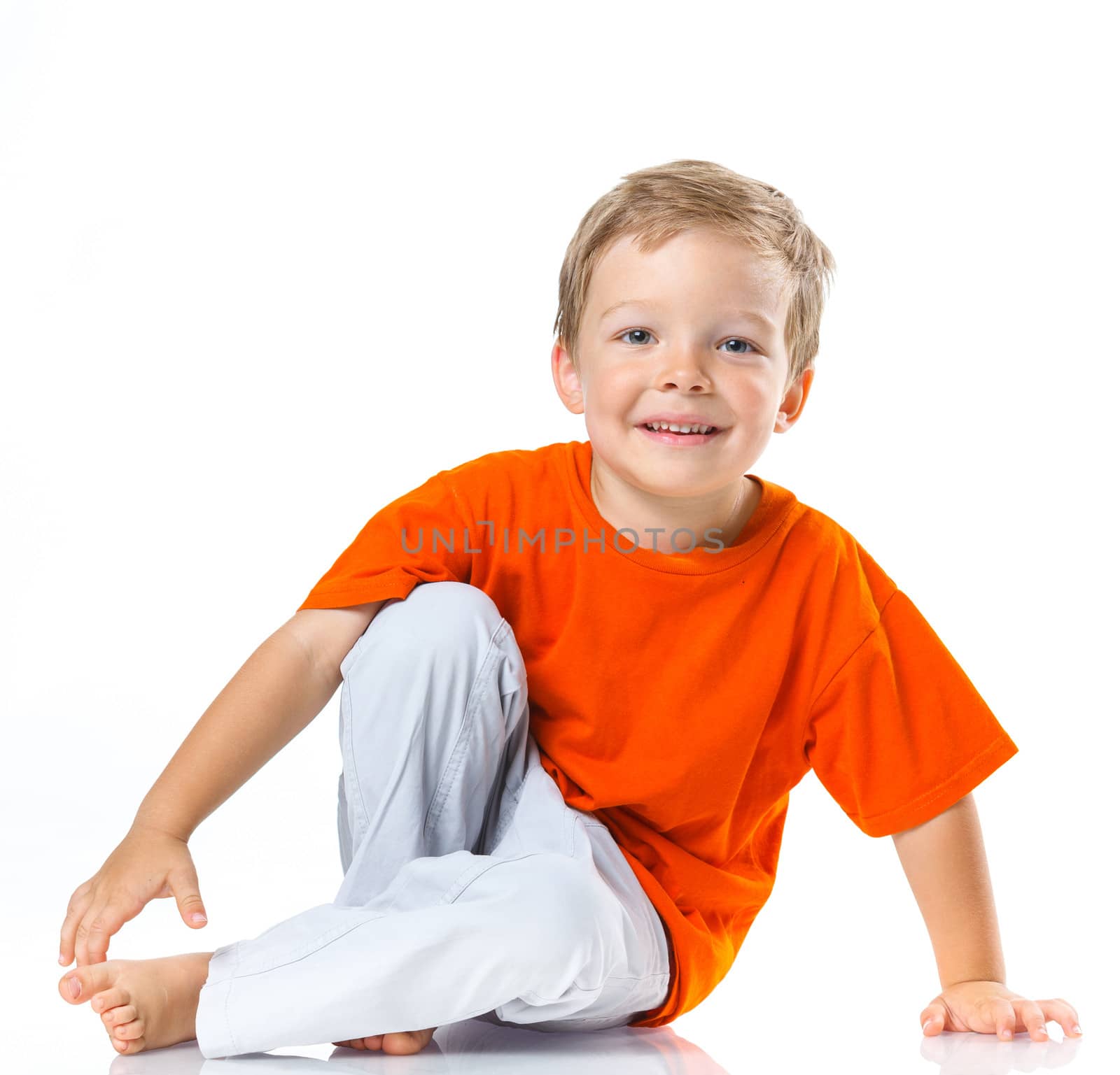 Adorable happy boy sitting on the floor in studio. Isolated of white background.