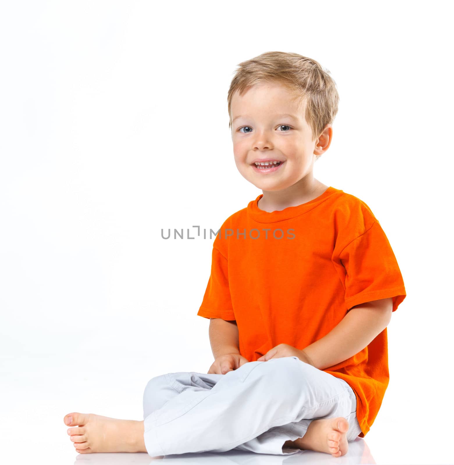Adorable happy boy sitting on the floor in studio. Isolated of white background.
