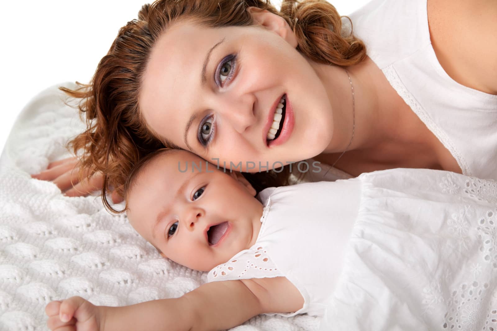 Portrait of beautiful young mother lying on bed with her small baby