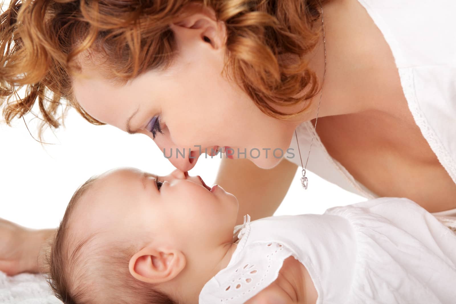 Closeup of loving mother playing with her little daughter on bed