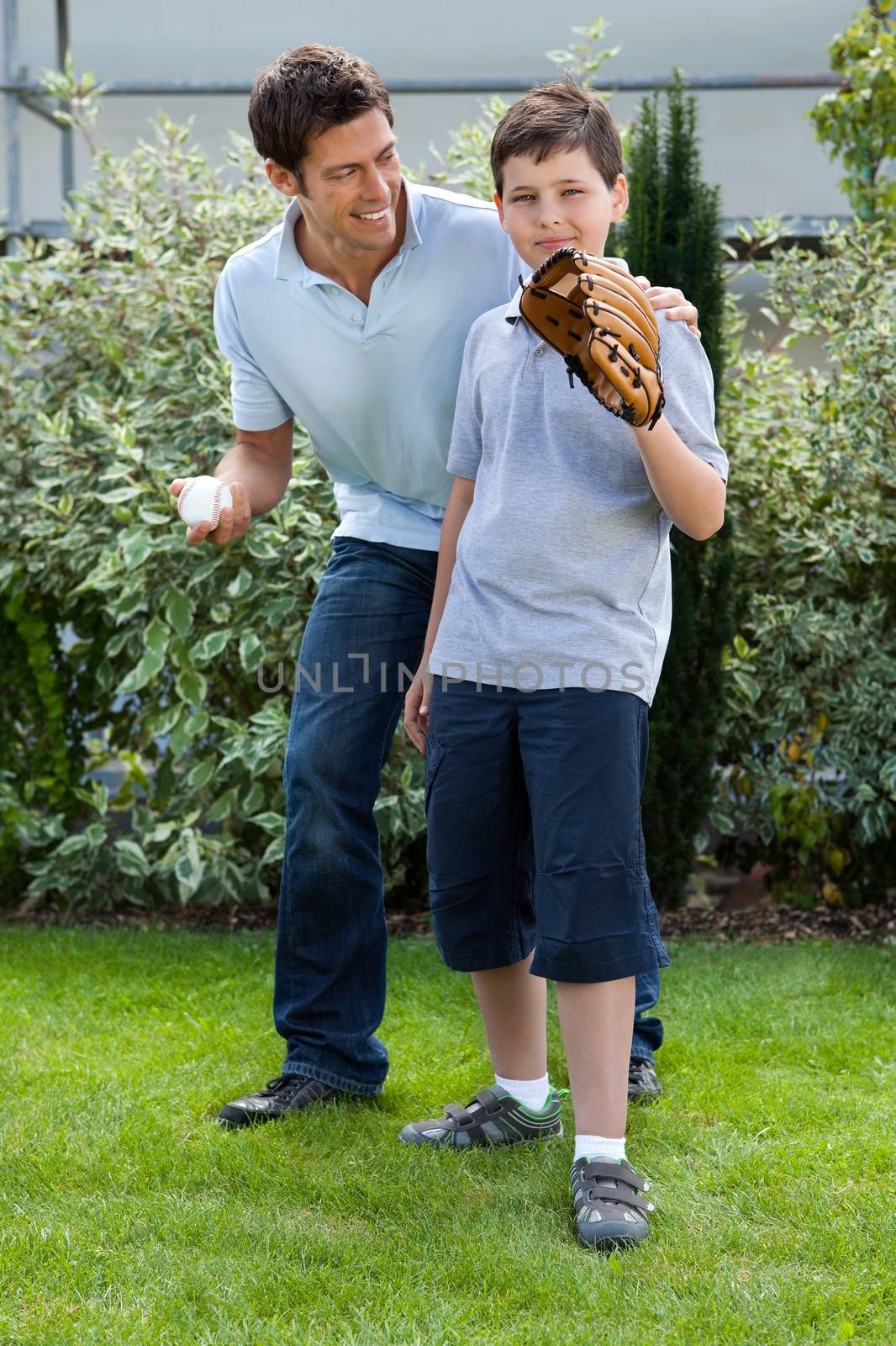Loving little boy playing baseball with his father in their backyard