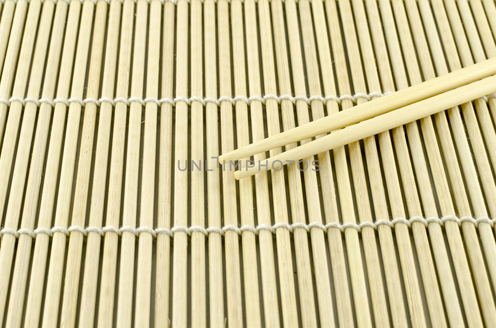 Two chopsticks on sushi mat background for menu