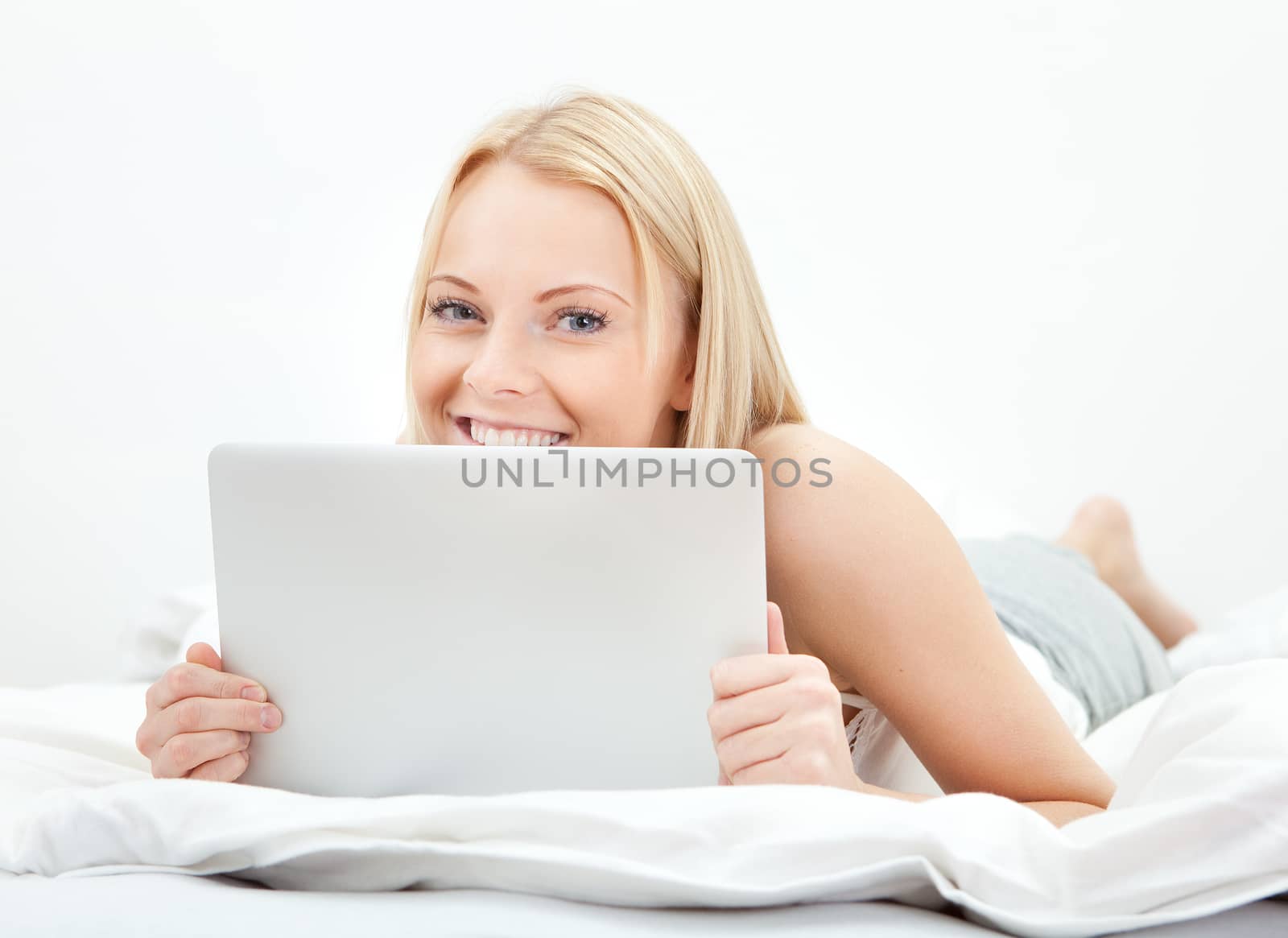 Young beautiful woman using laptop in bed at home