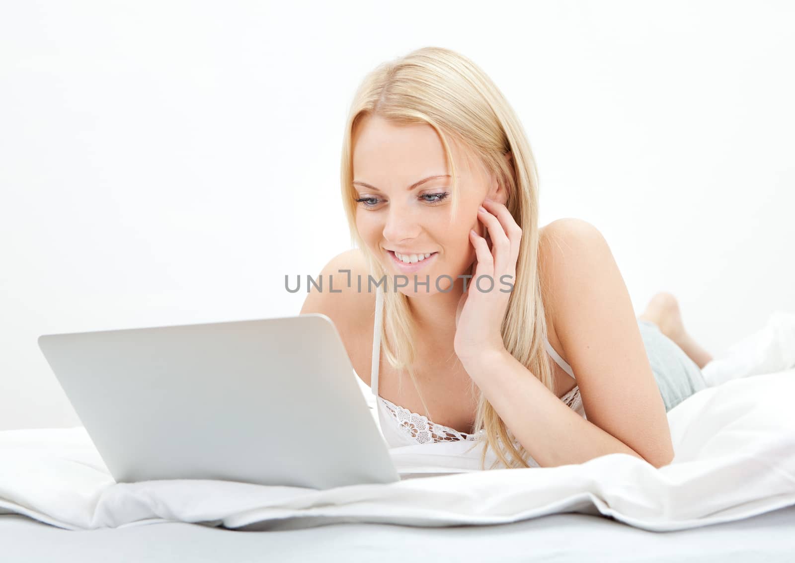 Young beautiful woman using laptop in bed at home