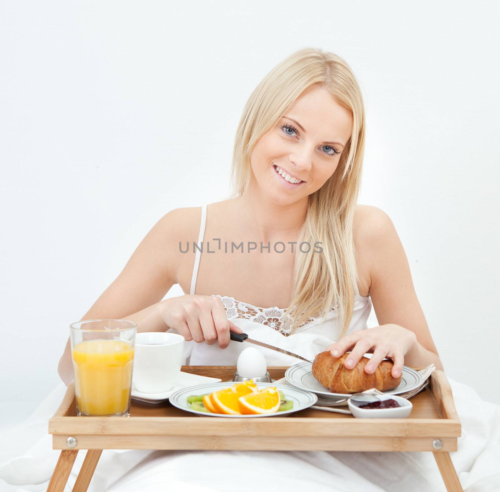 Beautiful woman cutting croissant while eating breakfast