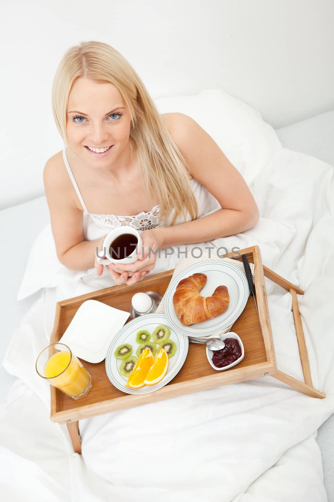 Beautiful woman drinking coffee in bed by AndreyPopov
