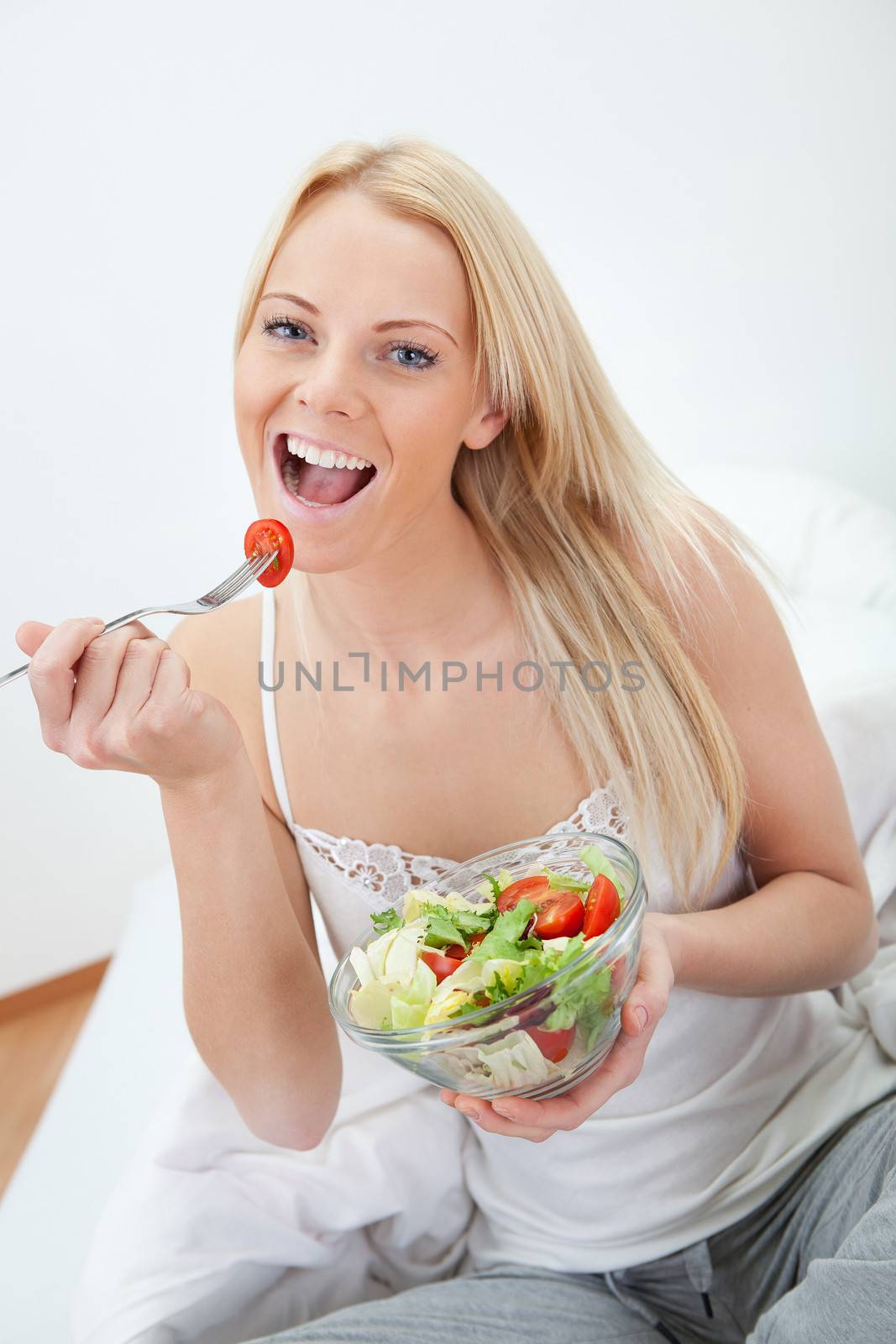 Beautiful woman eating green salad by AndreyPopov