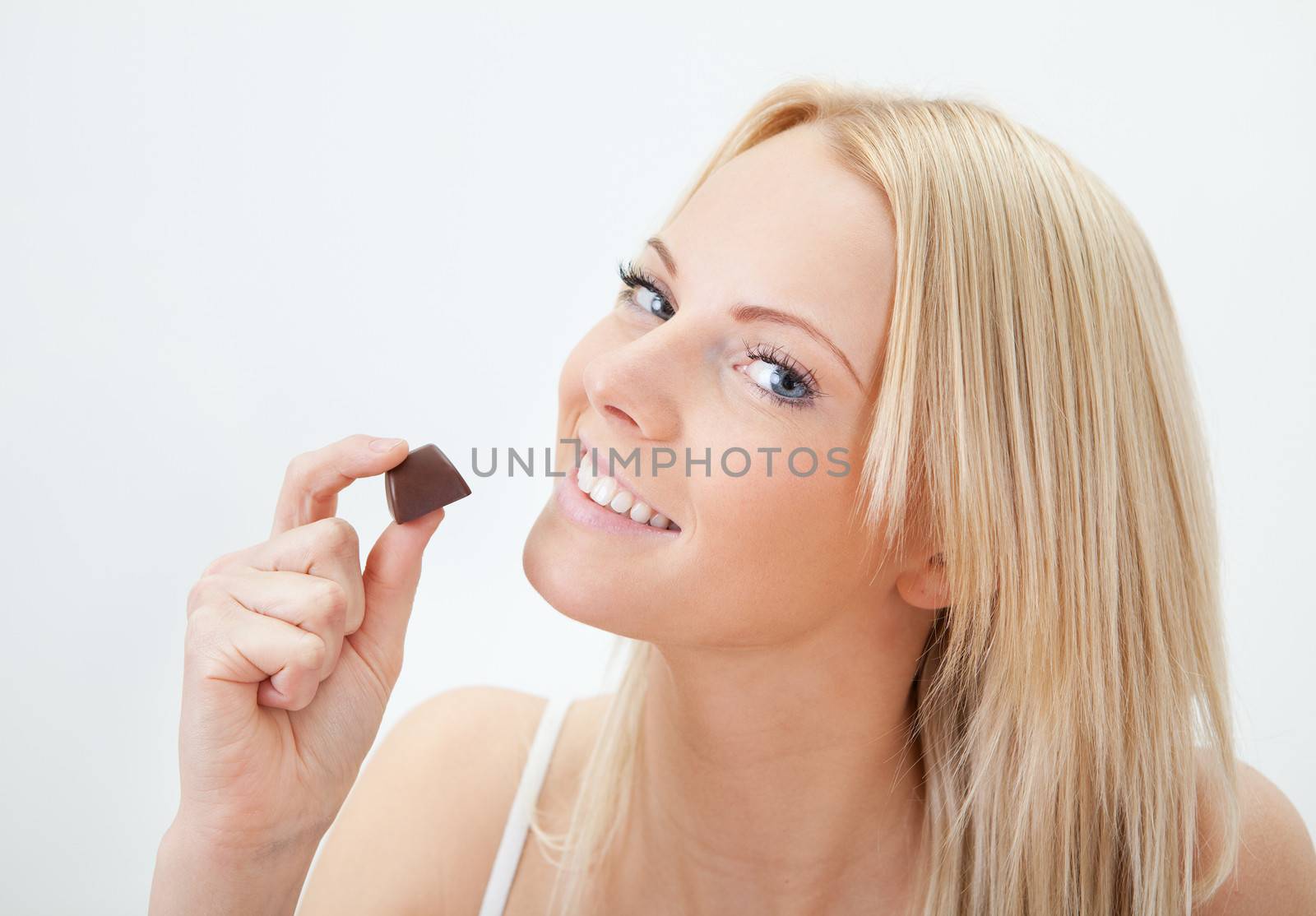 Beautiful young woman eating chocolate in bed