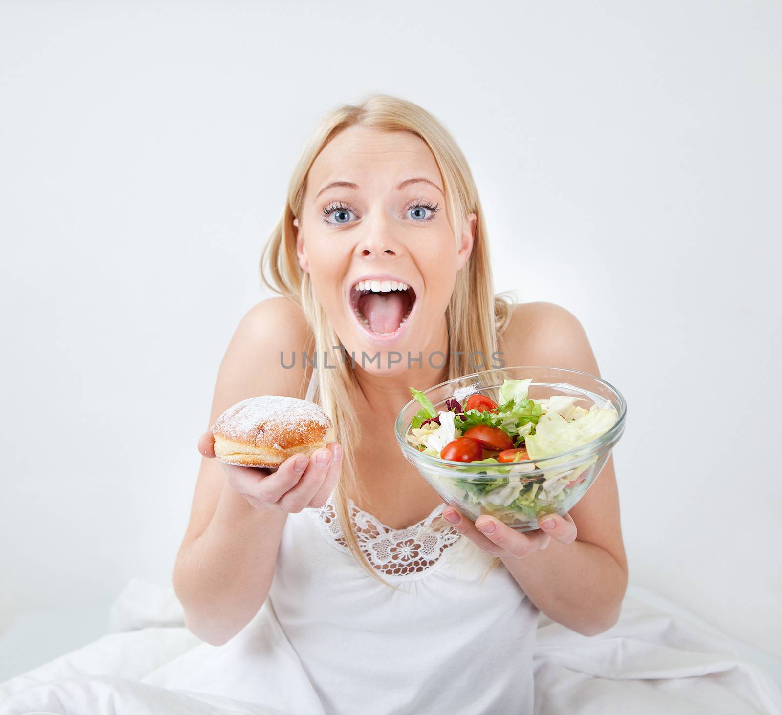 Tempted young woman making a choice between salad and donut