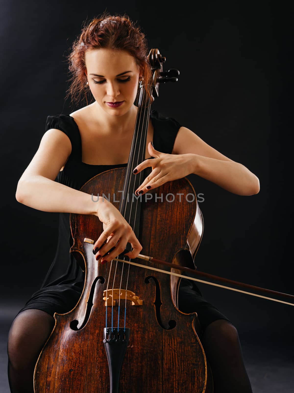 Photo of a beautiful female musician playing a cello.
