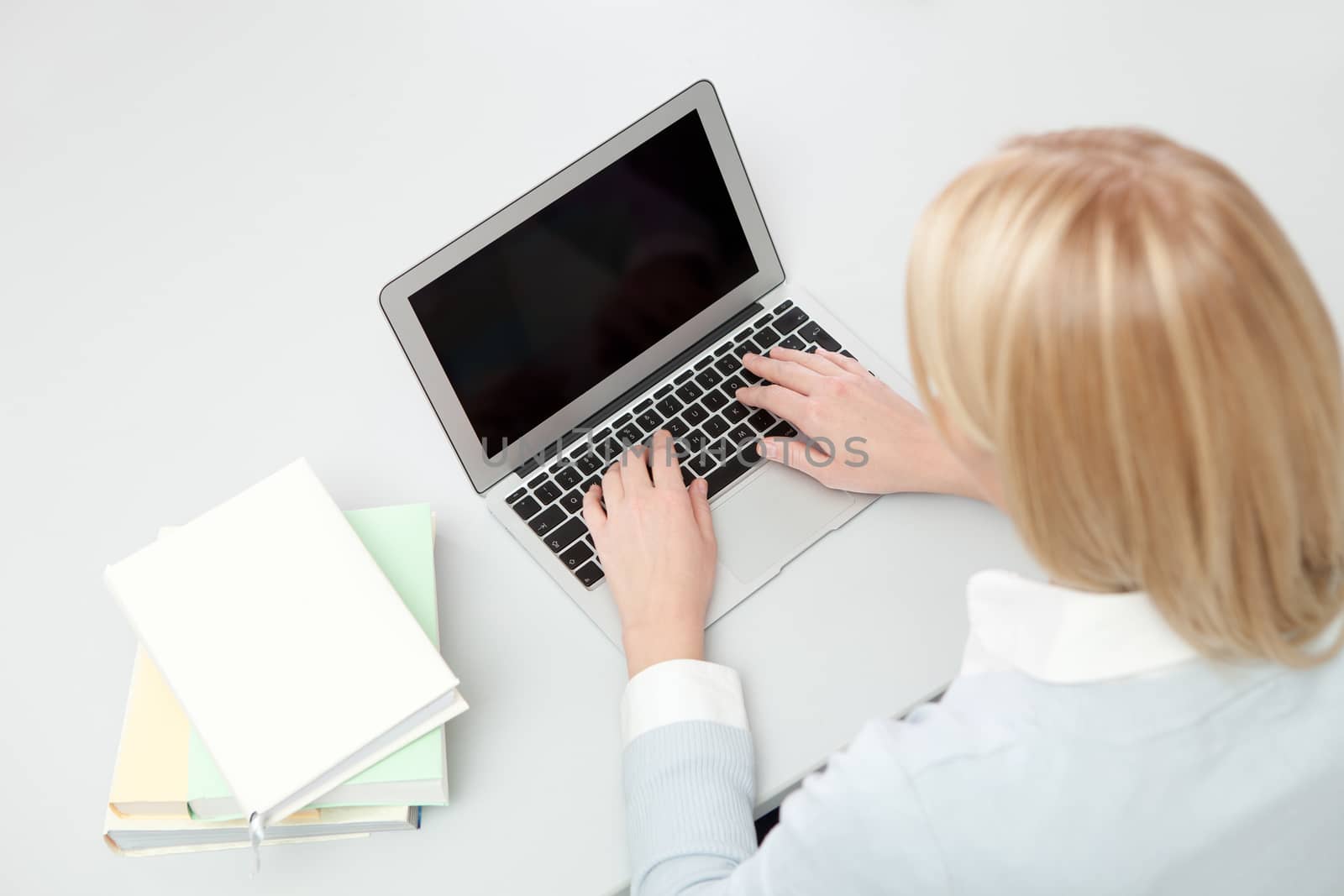 Beautiful student girl studying with laptop at the desk. Isolated on white