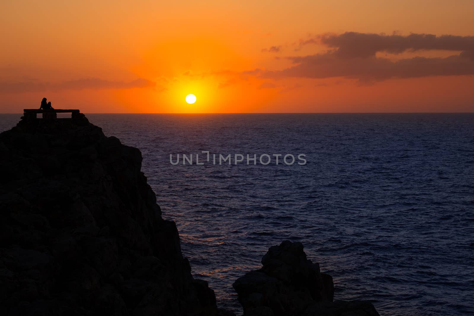 Ciutadella Menorca at Punta Nati orange sunset with girl backlight