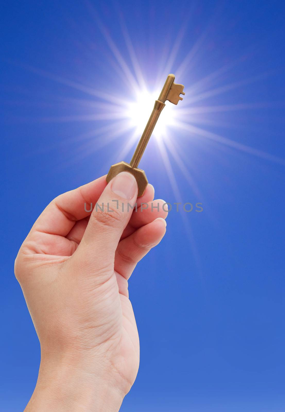 Hand holding a golden key against sky