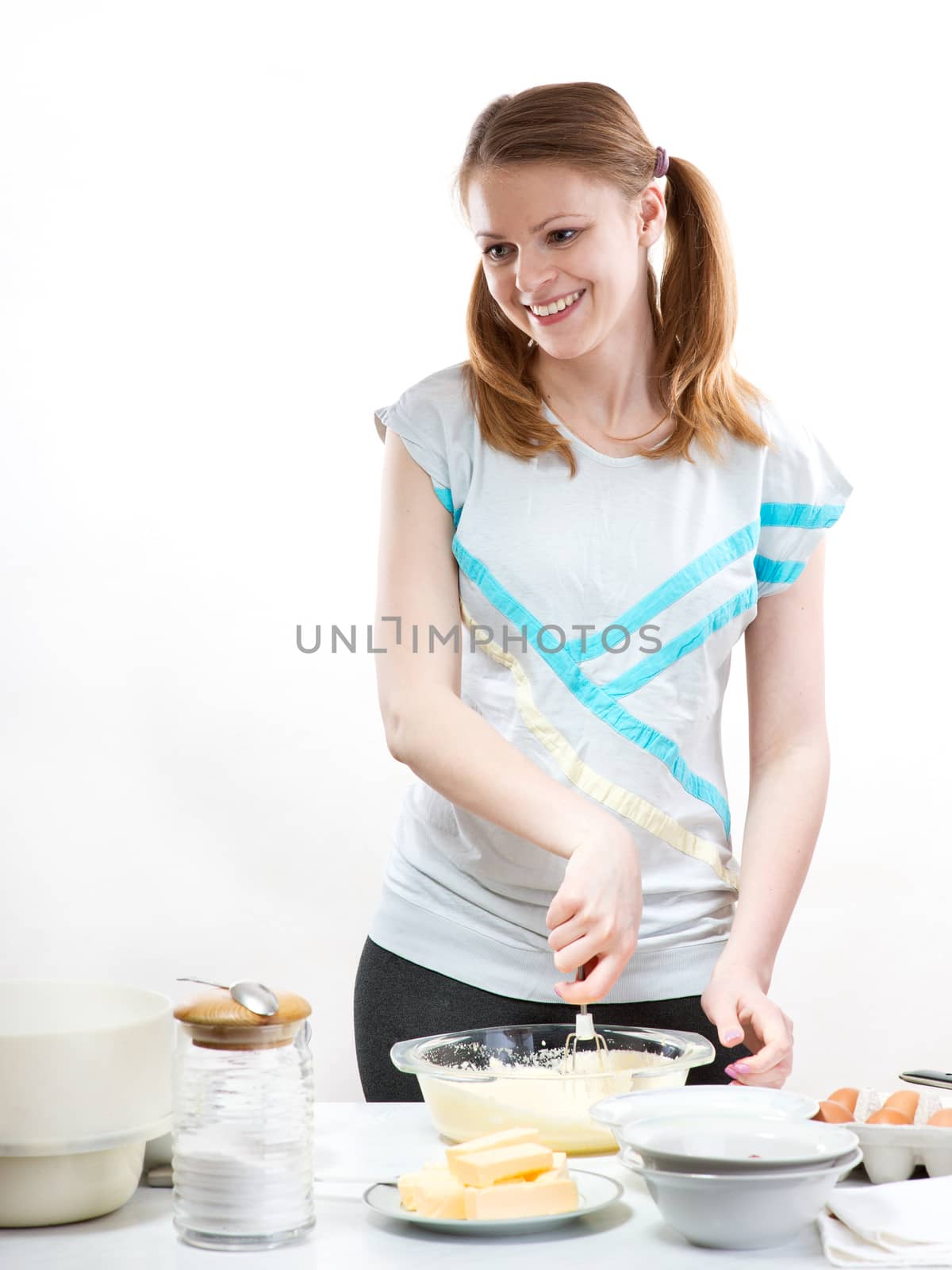 Beautiful pleasant girl prepares baking in kitchen by fotooxotnik