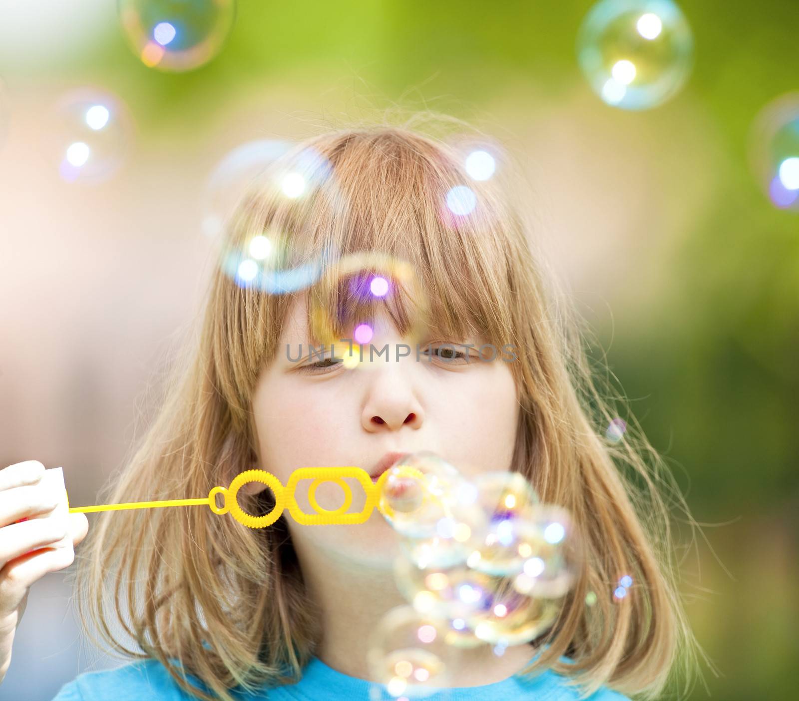 boy with long blond hair blowing soap bubbles