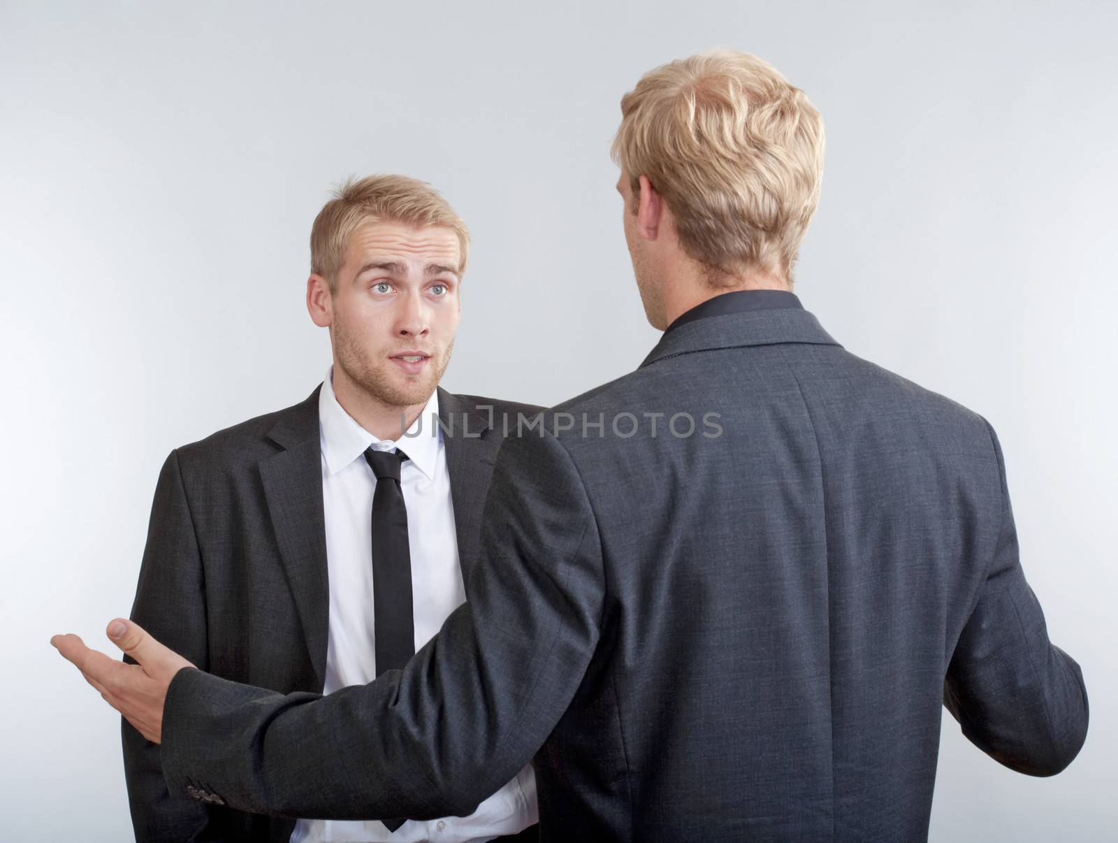 two you businessmen standing, discussing, arguing - isolated on light gray