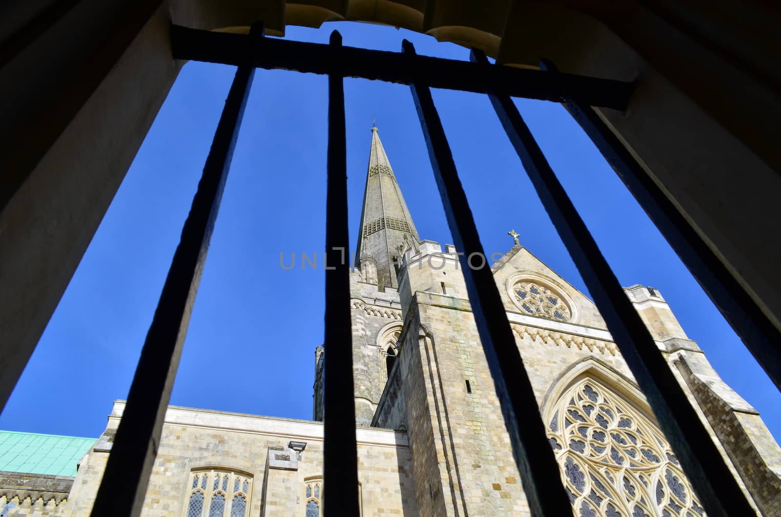 A view through iron railings of Chichester Cathedral and its majestic steeple.