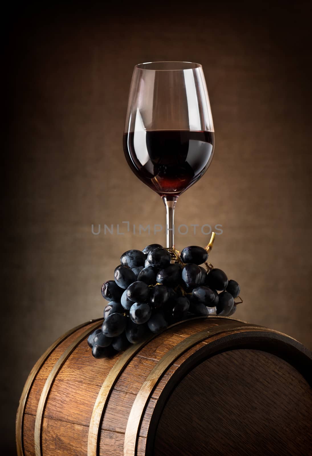 Wine goblet with wooden barrel and grape