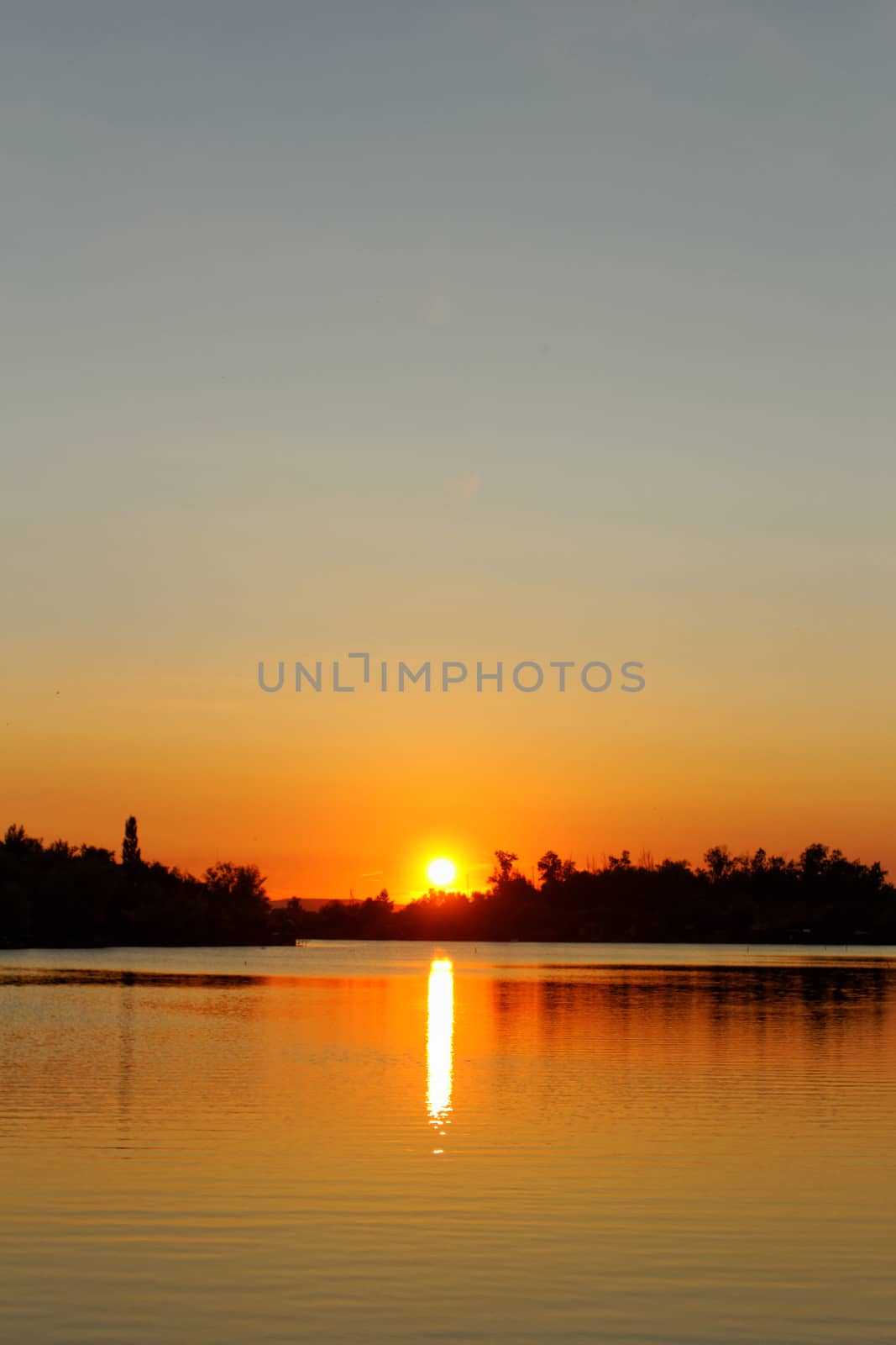 Colorful sunset over tranquil water surface.