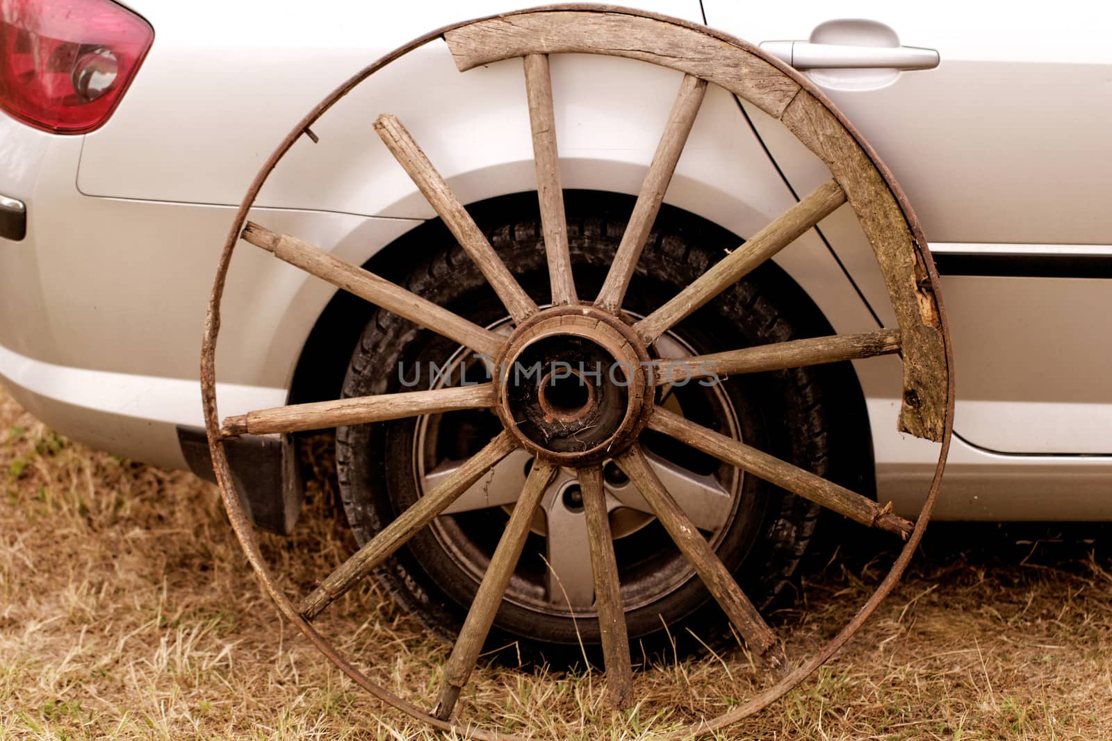 old broken wagon wheel side by new cars back