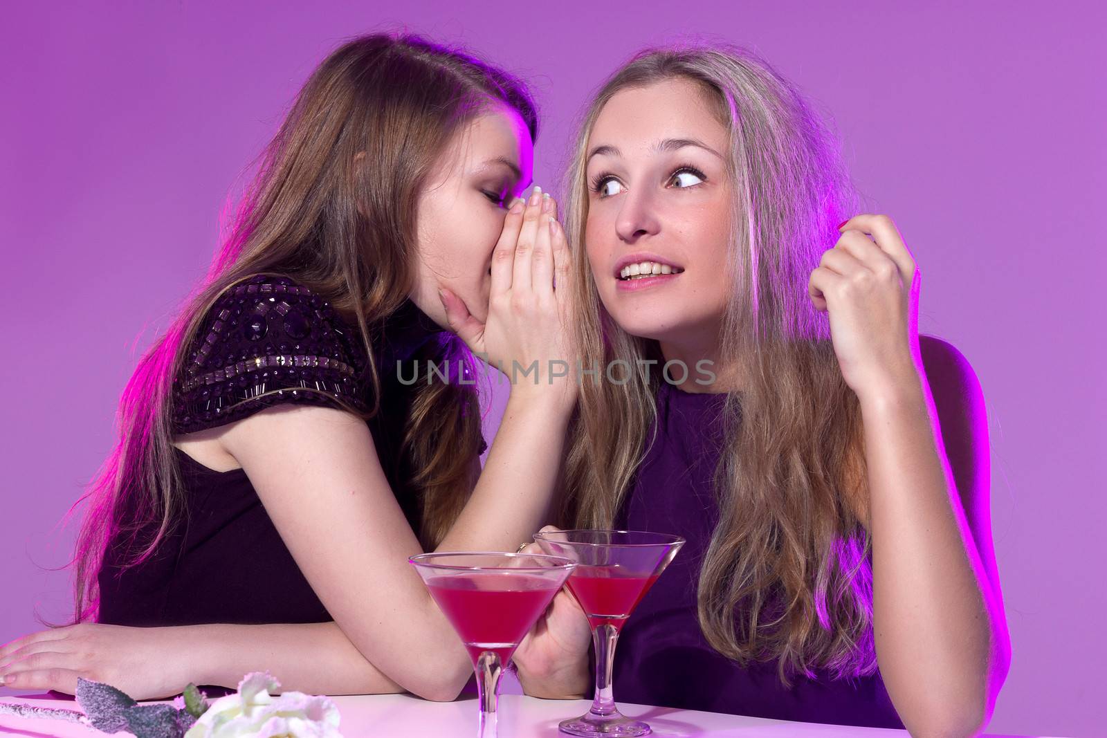 Female friends enjoying a night out sitting having cocktails at a table in a nightclub