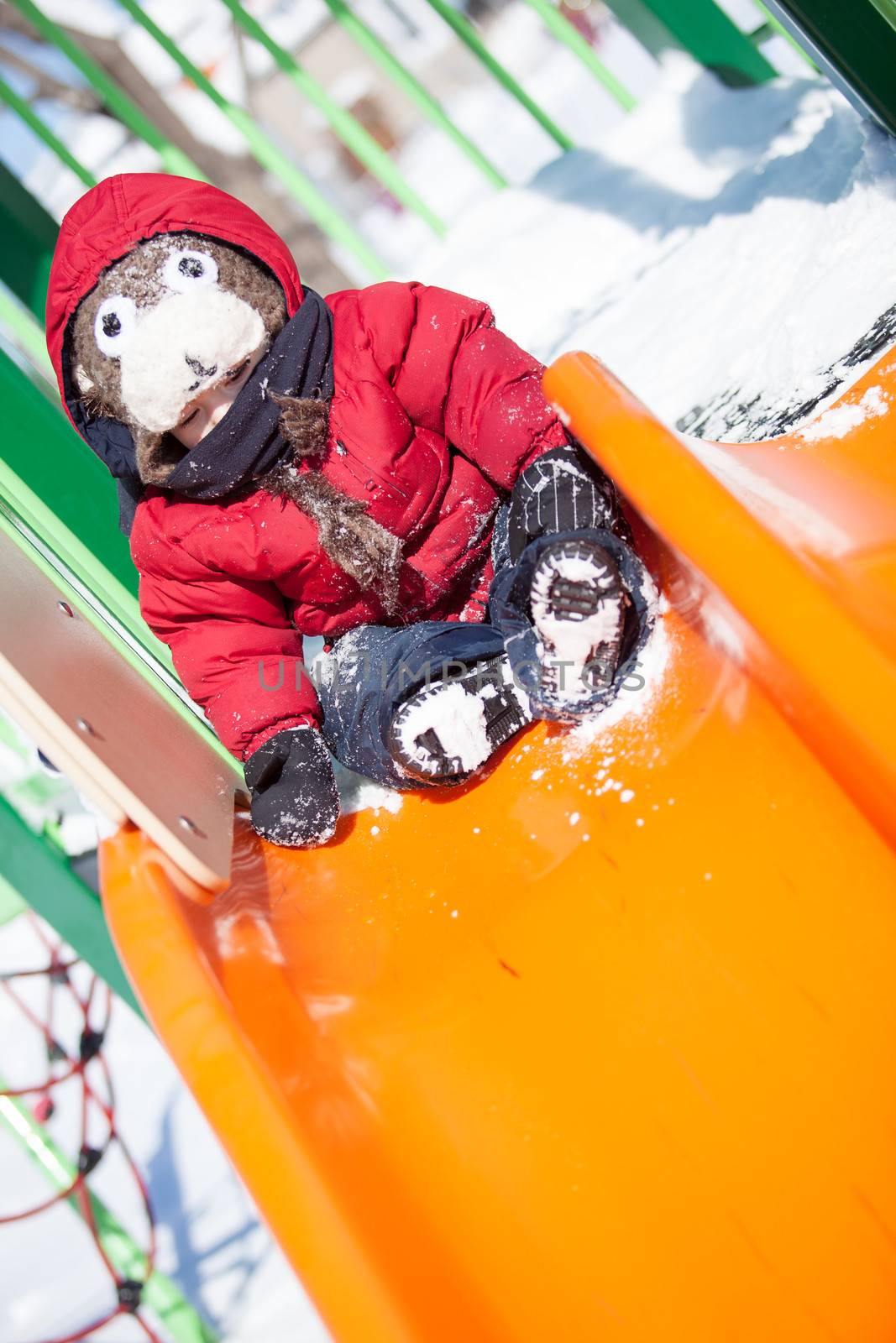 Infant playing on a slider in the snow