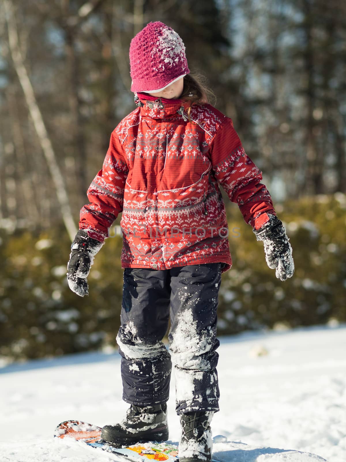 Girl playing in the snow with a snowboard