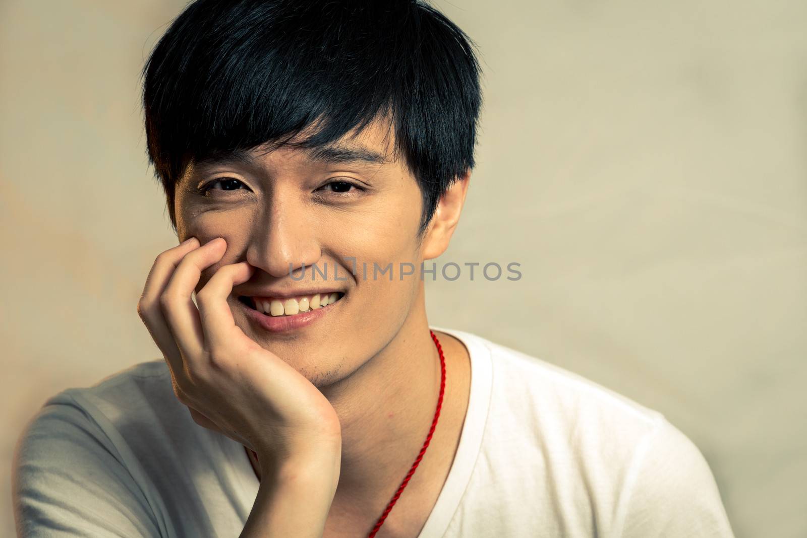 Young man supporting chin and smiling, with fashion tone and background