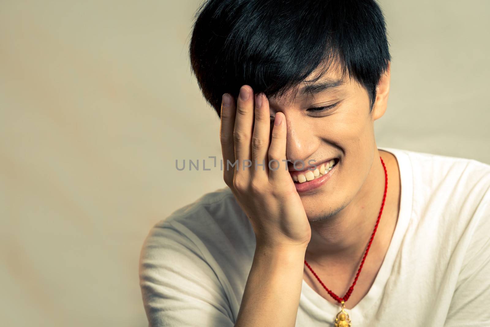 Young man covering his face and smiling, with fashion tone and background