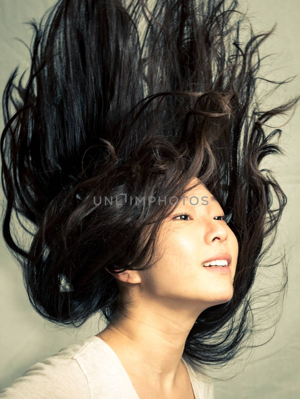 Young woman flicking her hair and posing, with fashion tone and background