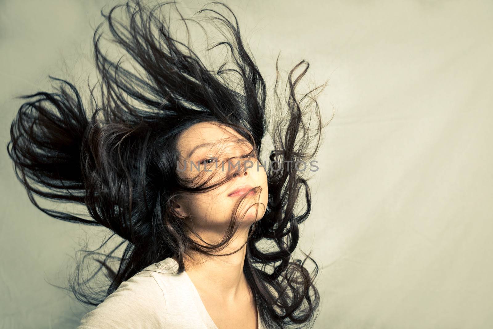 Young woman flicking her hair and posing, with fashion tone and background